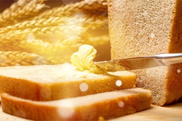 Slices of bread with butter on wheat background