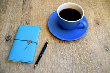Cup of coffee, pen and notebook on table