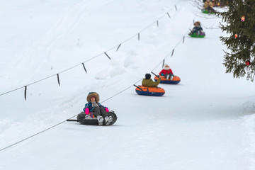 Fototapeta na wymiar Girl riding snow tube winter day