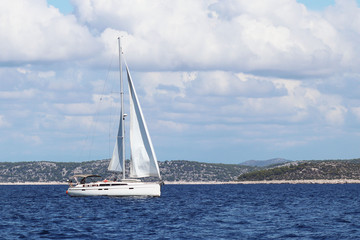 Fototapeta premium A sailing yacht is anchored in a bay. People bathe in the sea. Active rest on the Adriatic Sea of the Mediterranean region. Dalmatian riviera of Croatia. Prestigious and rich lifestyle