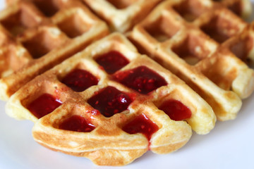 Belgian waffles with raspberry jam in white plate. Tasty breakfast close up, freshly baked classic wafer