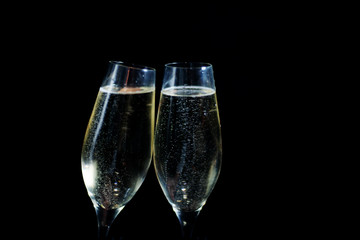 two glasses of white champagne on black background.