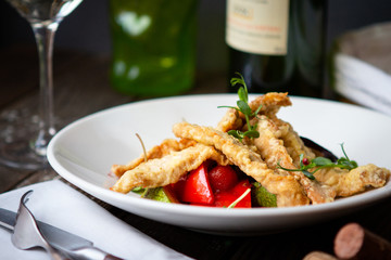 white fish fried in slices with vegetables on a white plate