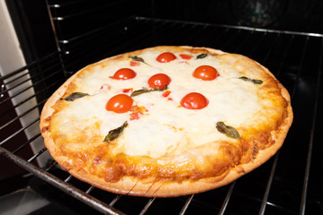 Pizza making closeup with tomatoes and cheese from the oven