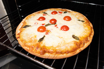 Pizza making closeup with tomatoes and cheese from the oven