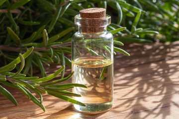 A bottle of rosemary essential oil with fresh rosemary