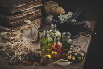 Bottles of essential oil, mortar of dried moss, old books, dry roots and plants. Herbal medicine.