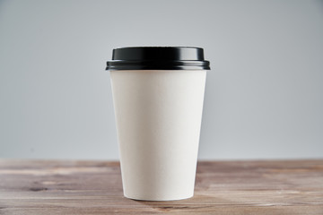 White Paper coffee cup disposable for take away or to go, at wooden table, space for design layout.