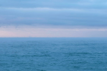 Naklejka na ściany i meble Beautiful seascape with pink sunset and blue clouds. Calm sea.