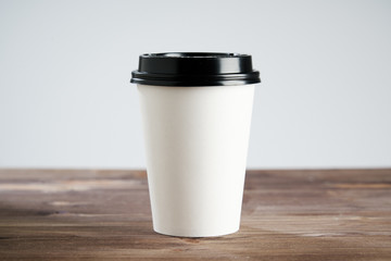 Paper  coffee cup disposable for take away or to go, at wooden table, space for design layout.