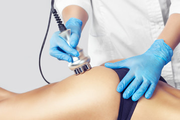 The doctor does the Rf lifting procedure on the legs, buttocks and hips of a woman in a beauty...