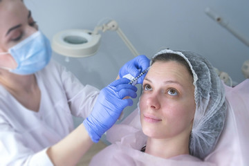 Contour plastic face. Rejuvenating facial injections procedure for tightening and smoothing wrinkles on the face skin of a beautiful young woman in a cosmetology clinic.