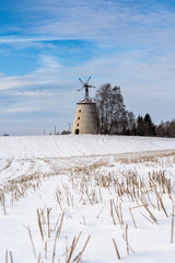 Obraz premium Empty Countryside Landscape in Sunny Winter Day with Snow Covering the Ground with Big Abandoned Windmill in Background