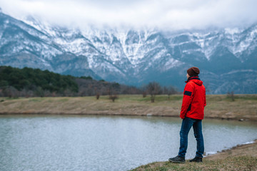 A young tourist looks at the picturesque landscape of snow-capped mountains.
