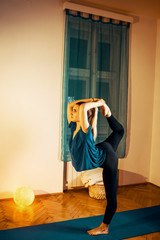 Blonde woman doing dancers pose in yoga exercise.