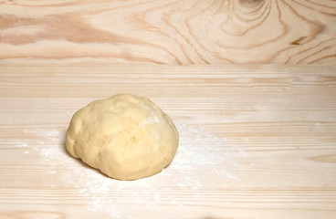 Homemade dough with flour on wooden background. Dough on the background with a place for copispeysa. Homemade cakes, bread, dumplings, dumplings