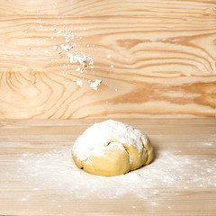 Homemade dough with flour on wooden background. Dough on the background with a place for copispeysa. Homemade cakes, bread, dumplings, dumplings