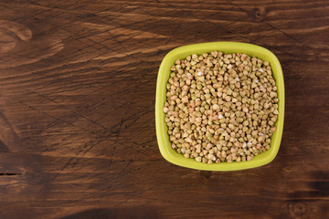 Natural fresh green buckwheat in ceramic bowl on wooden background. Top view