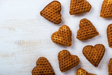 Heart-shaped cookies with jam and candy, above the head on a white wooden table.
