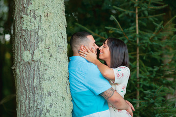 Young fashionable couple in love and kissing outside by tree