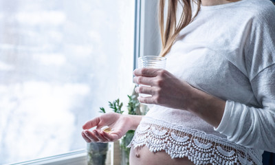 Conceptual photo of pregnancy healthcare. Pregnant woman taking pills during pregnancy. Last months of pregnancy. 