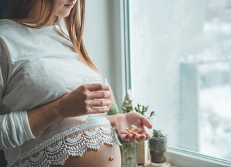 Conceptual photo of pregnancy healthcare. Pregnant woman taking pills during pregnancy. Last months of pregnancy. 