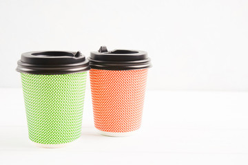 Green and red eco paper cups on white background with copy space