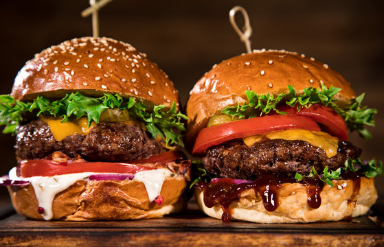 Tasty burgers on wooden table.