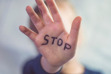 Concept of domestic violence and child abusement. A little girl shows her hand with the word STOP written on it. Children violence. - obrazy, fototapety, plakaty