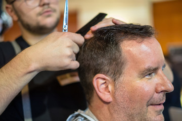 Obraz premium Happy guy getting haircut by hairdresser