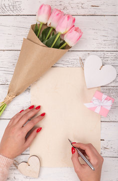Empty blank paper with woman's hands. Background with pink roses in vase.