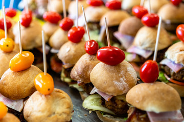Closeup View of Small Handmade Burgers on the Table with Pickles, Tomatoes, Pork Cutlets and Salads as Ingredients - Kitchen Set