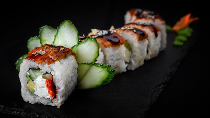 Sushi Roll Dragon, on black stone, on black background, close up