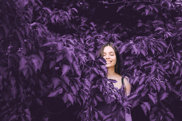 Adorable kid girl playing with blooming lilac flowers in spring garden, eyes closed
