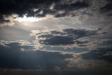 Sun lights coming through clouds. Skyscape at sunset.