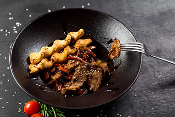 A meat dish with bread sticks and spices on black background