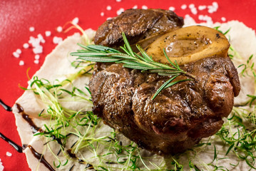 Grilled meat steak on pita leaf in a red plate