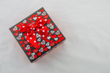 Valentines day! A gift box, black with red and white hearts on which love messages written, isolated on a white background. Top view.
