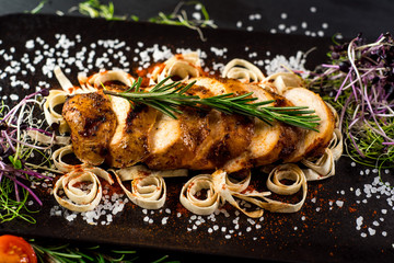 Grilled chicken meat medallions on black background