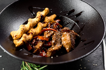 A meat dish with bread sticks and spices on black background