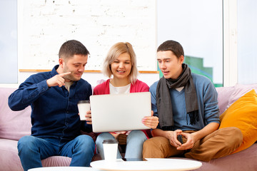 Fototapeta premium Friends sit on the couch, chatting and using a smartphone, desktop computer, laptop.