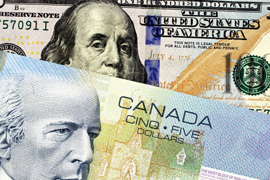 A close up image of a blue Canadian five dollar bill with an American one hundred dollar bill