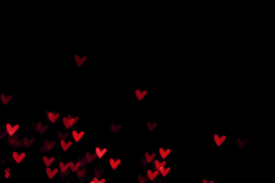 Red heart valentine bokeh lights against a black background