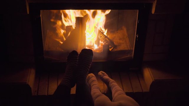 POV shot legs of parent and child enjoying and relaxing near fireplace close-up