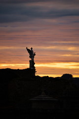 Sunrise in a cloudy day over the guardian angel of the cemetery of Comillas, Cantabria