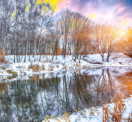 Winter landscape by a river in the sunset