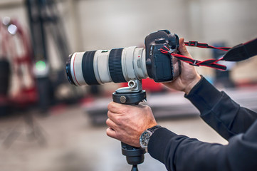 Videographer using stadicam, making video of machine at factory