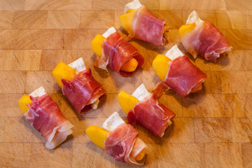 Tapas of Serrano ham, goat cheese, peach, on wooden board