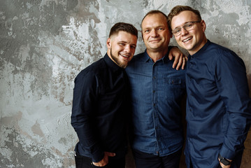Dad and his young sons. Two adult sons are standing with their beloved dad on gray background