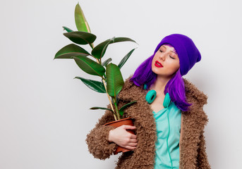 Beautiful young girl with purple hair in jacket with plant on white background.